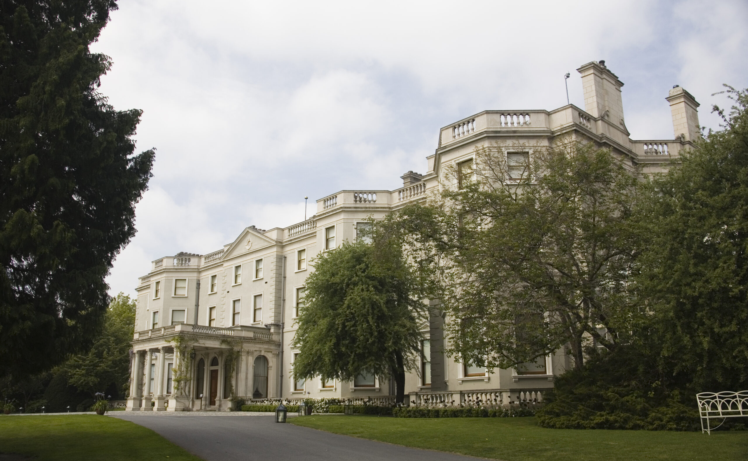 The front of Farmleigh house, a Georgian house with a grand porch, obscured by some trees