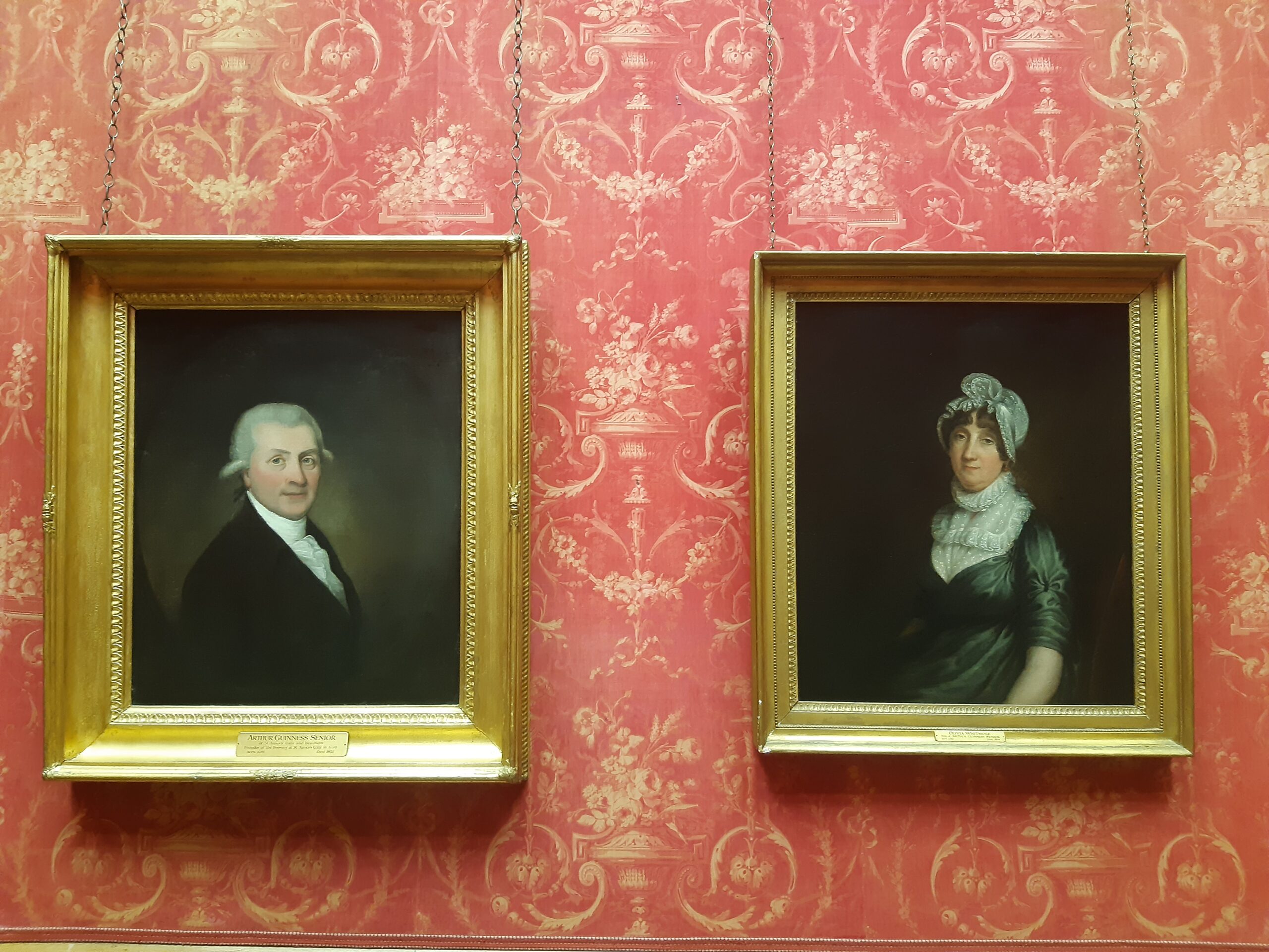 Portrait paintings of Arthur & Olivia Guinness on red background