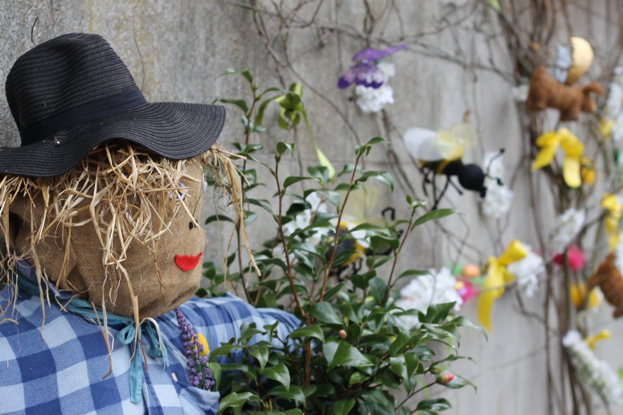 Scarecrow in front of wall with decorative bees and other insects