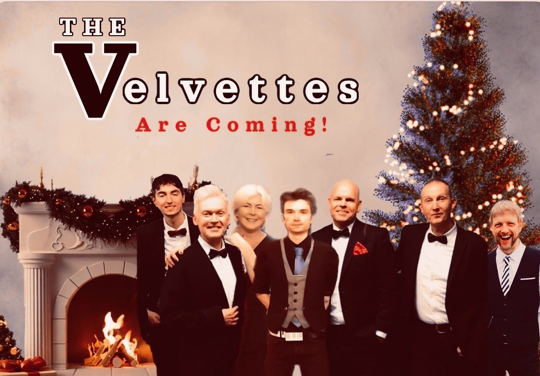 Singers in black tie standing between fireplace and Christmas tree